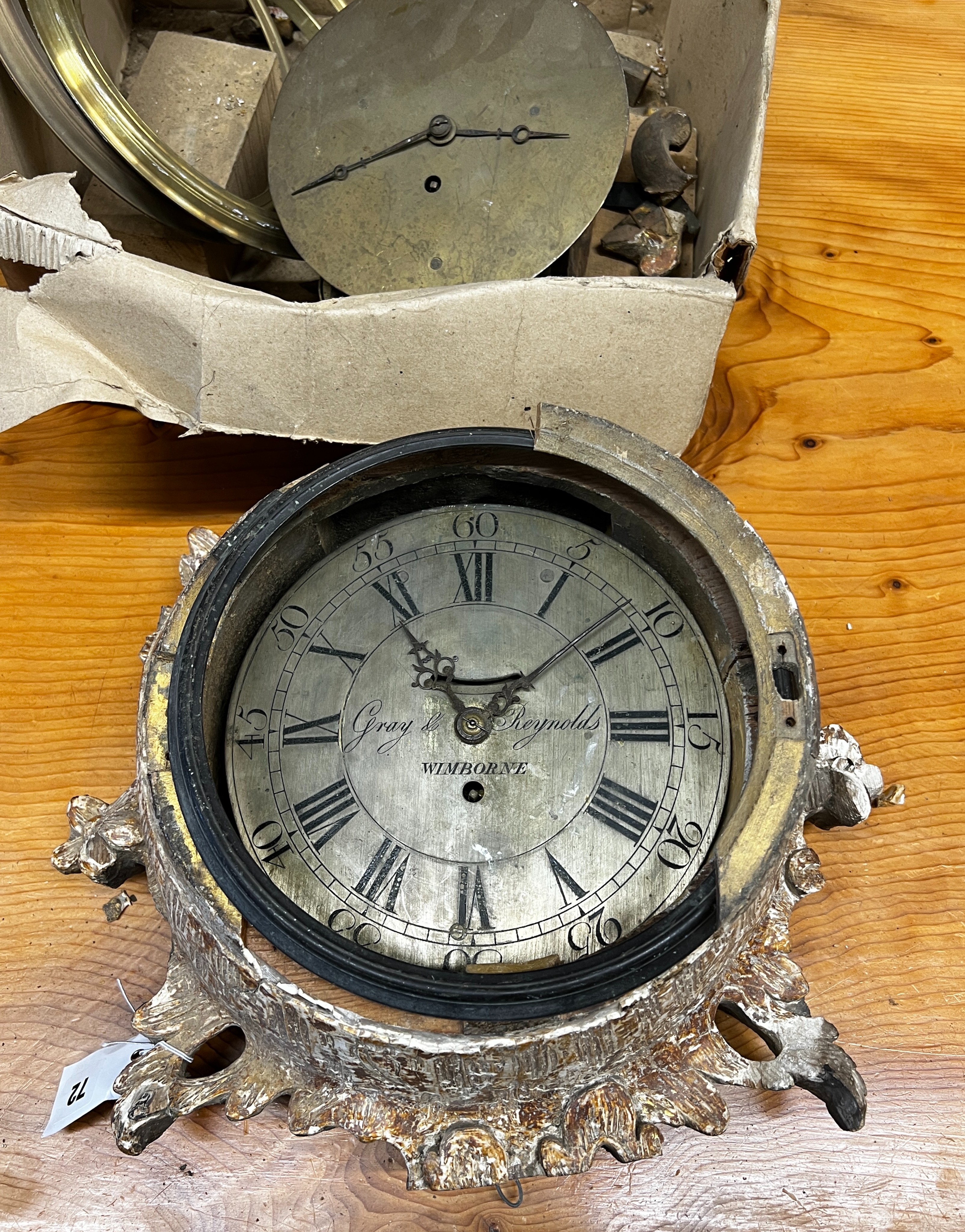 An early 19th century carved giltwood single fusee wall dial, marked Gray and Reynolds, Wimborne, dial diameter 23cm (in need of restoration), together with one other movement and three clock bezels